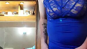 Crossdressing-Schönheit in einem blauen Kleid neckt mit ihren Titten und ihrem Schwanz