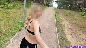 אישה בלונדינית מתאמנת בחוץ בפארק, חושפת את גופה העירום ושדיה המקפצים